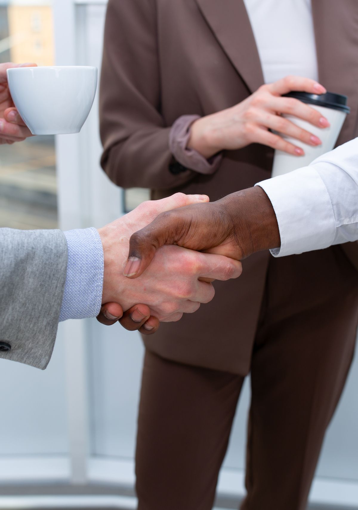 Profesionales diversos se dan la mano durante una reunión de negocios en oficina corporativa
