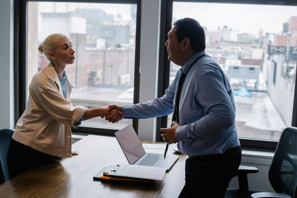 Dos profesionales estrechan la mano tras una reunión de negocios en una oficina moderna