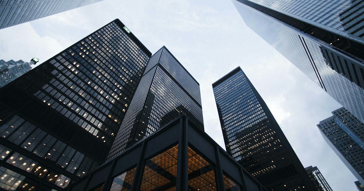 Edificio corporativo moderno con fachada de cristal que refleja el cielo